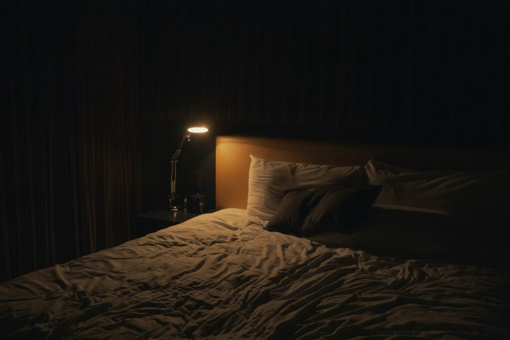 A small, dim lamp illuminates a bed during an evening routine